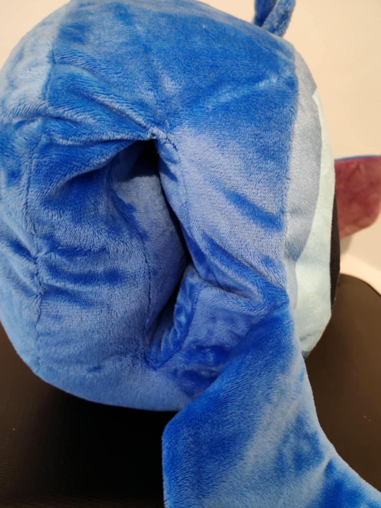 Zijkant van een blauw Stitch pluche handwarmer kussen met zachte oren en opening voor de handen.